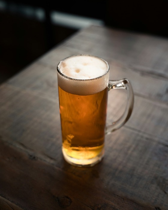 Sfeerbeeld (Unsplash): een glas bier op een houten tafel