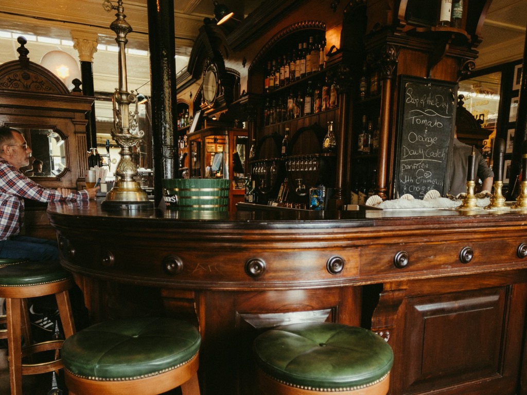 Sfeerbeeld (Unsplash): houten toog in een bruin café